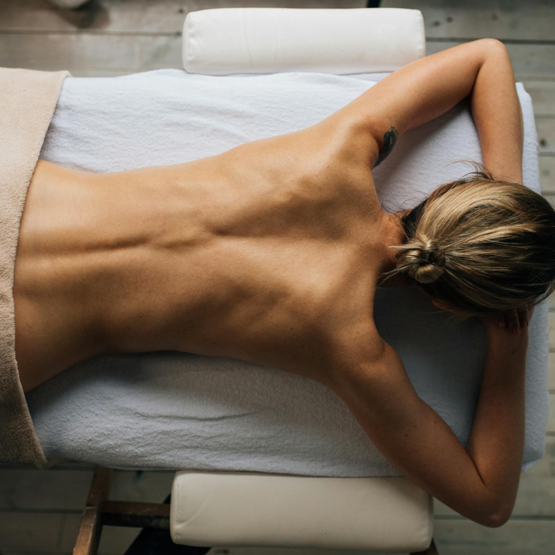 Femme allongée, prête pour un massage détente thérapeutique visant à soulager douleurs chroniques, réduire stress et améliorer bien-être global